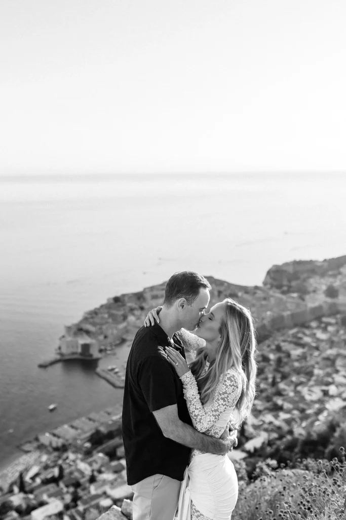 black and white photo of couple kissing with great mountain view at dubrovnik